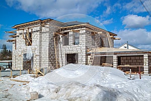 exterior of country house under construction with scaffolding and holders for gutters water drainage system of roof. Site on which