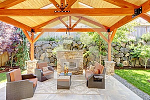 Exterior covered patio with fireplace and furniture.