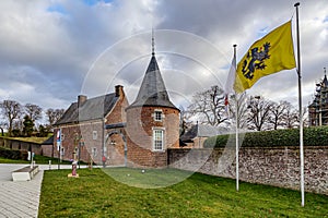 Exterior of former 16th century Alden Biesen castle, yellow Flanders flag with black lion and red tongue