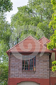 Exterior of a home with red hip roof over the window and stonr brick wall