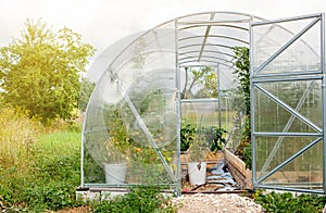 Exterior of home use new plastic greenhouse in warm summer day.