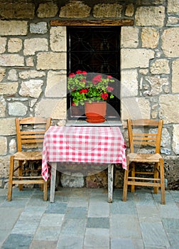 Exterior house with old chairs and table on stone street. Zarouhla village, Greece