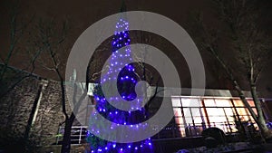 Exterior of modern house or restaurant, the Christmas lights are lit on the trees, in the night sky, camera movement