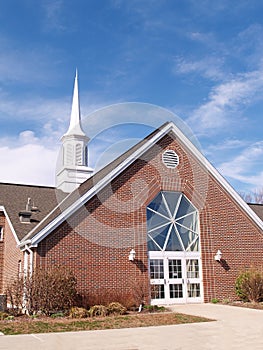 Exterior of a modern red brick church and steeple photo