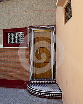 Exterior mosaic surrounded wooden door to a residence in the old medina of Marrakesh, Morocco.