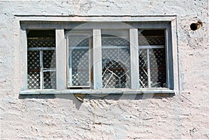 Exterior of an old abandoned cottage with broken glass and white cracked wall