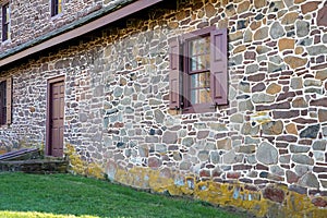 Exterior of old stone colonial American home with window shutters