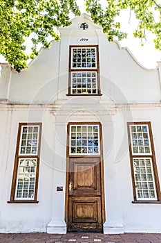 Exterior of an old white house in the style of the Dutch Cape architecture in Stellenbosch, Western Cape, South Africa