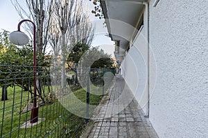 Exterior perimeter corridor with metal fence around a residential building with landscaped common areas
