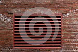 Exterior red brick wall with large painted industrial vent, weathered commercial building