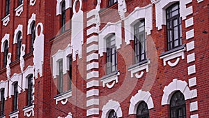 Exterior of red and white brick building with dark windows. Stock footage. Public facility in the city street.