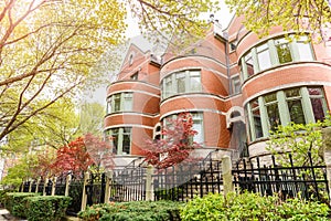 Exterior of a row of brick town houses along a pavement lined with trees in spring