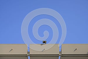 Exterior security camera on the roof buidling over blue sky background