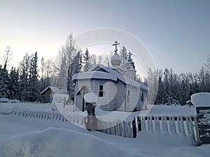 Exterior of St Nicholas Russian Orthodox Church in Eklutna, Alaska on a Clear Winter Day, White Wooden Church