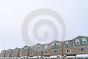 Exterior of townhouses with gable roofs and brick wall against cloudy sky