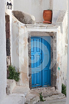 Exterior of traditional greek house - background with blue door, white steps and flower pot