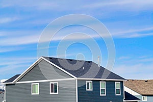 Exterior of upper floor of home with gable roof and gray horizontal wood wall