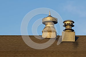 Exterior view of air vent and chimney on a old barn roof against blue background