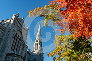 Exterior view of the Basilica of Sainte-Anne-de-Beaupre church with red maple tree