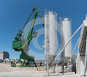 Exterior view of a cement factory with crane and concrete mixing silo