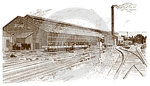 Exterior view of a historical factory building with rails, wagons and a smoking chimney in front of it