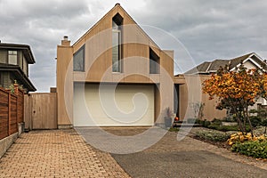 Exterior view of modern house with garage decorated with wood. Luxury real estate single family house with wooden facade