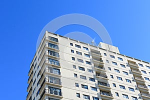 Exterior view of a typical multifamily mid and high rise residential building under blue sky. Looking up at rental apartment,