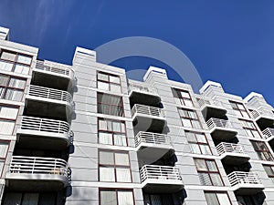 Exterior view of typical multifamily mid-rise residential apartment building with balconies and identical windows blinds under