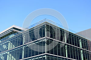 Exterior view of a vacant brand new modern office building. Typical glass facade of generic modern commercial building. Blue sky.