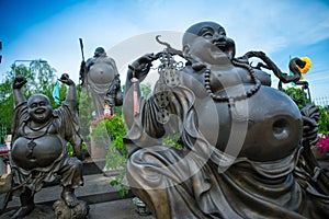 Smiling happy buddhist statues against blue sky at Viharn Sien temple photo