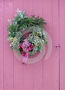 Exterior wall of rustic red barn with pretty wreath on door