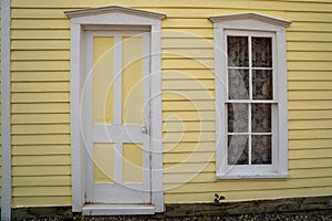 Exterior of a yellow painted home, door and window with white trim. Taken in South Park Colorado, a ghost town