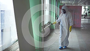 Exterminator in overalls and a protective mask carries out processing of the room