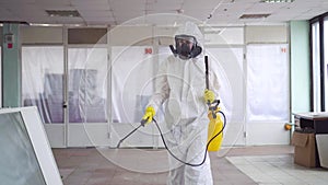 Exterminator in overalls and a protective mask with a sprayer