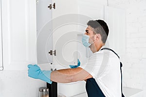 Exterminator in uniform looking at kitchen