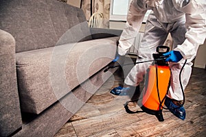 An exterminator in work clothes sprays pesticides with a spray gun. Fight against insects in apartments and houses