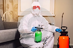 An exterminator in work clothes sprays pesticides with a spray gun. Fight against insects in apartments and houses