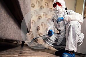 An exterminator in work clothes sprays pesticides with a spray gun. Fight against insects in apartments and houses