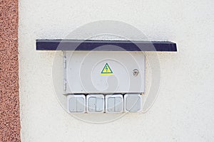 External electrical box with lock is placed on wall of house from the outside. Beware of electricity!