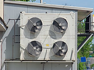 An external fan unit from air conditioners is attached to the facade of an industrial building.