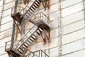 External metal staircase on the facade of an abandoned factory or enterprise building