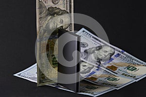External solid state drive standing among US dollar and euro banknotes on black background