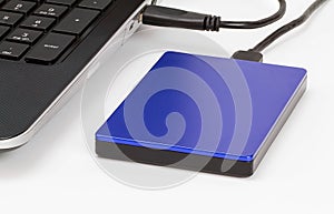 External storage connected to laptop by usb cable on white desk