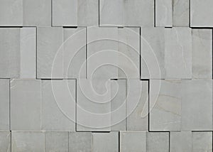 External wall made of horizontal gray granite tiles assembled vertically in relief.