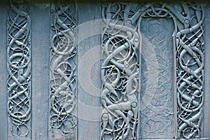 External wooden wall carved decoration of the medieval Urnes Stave church with viking motifs covered with tar in Ornes, Norway.