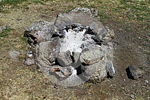 Extinct camp fire place with ashes surrounded with rocks or stones, photo of nature