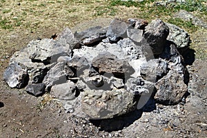 Extinct camp fire place with ashes surrounded with rocks or stones, photo of nature