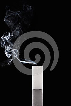 Extinct white candle with smoke on black background