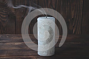 Extinguished big candle in the dark. On a wooden background. Candle smoke