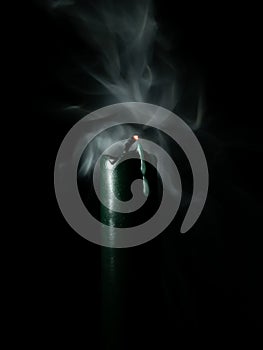 Extinguished green candle on pure black background, light painting